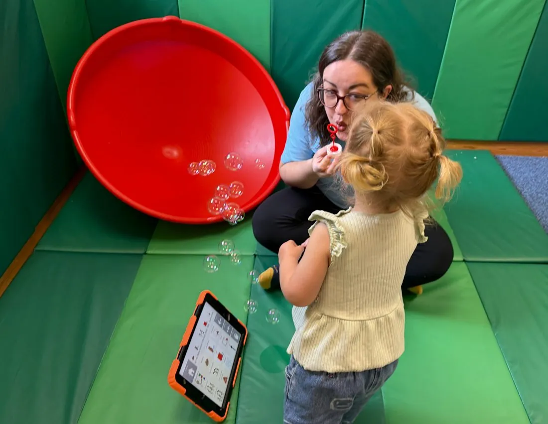 Therapist blowing bubbles with a child during a speech therapy session